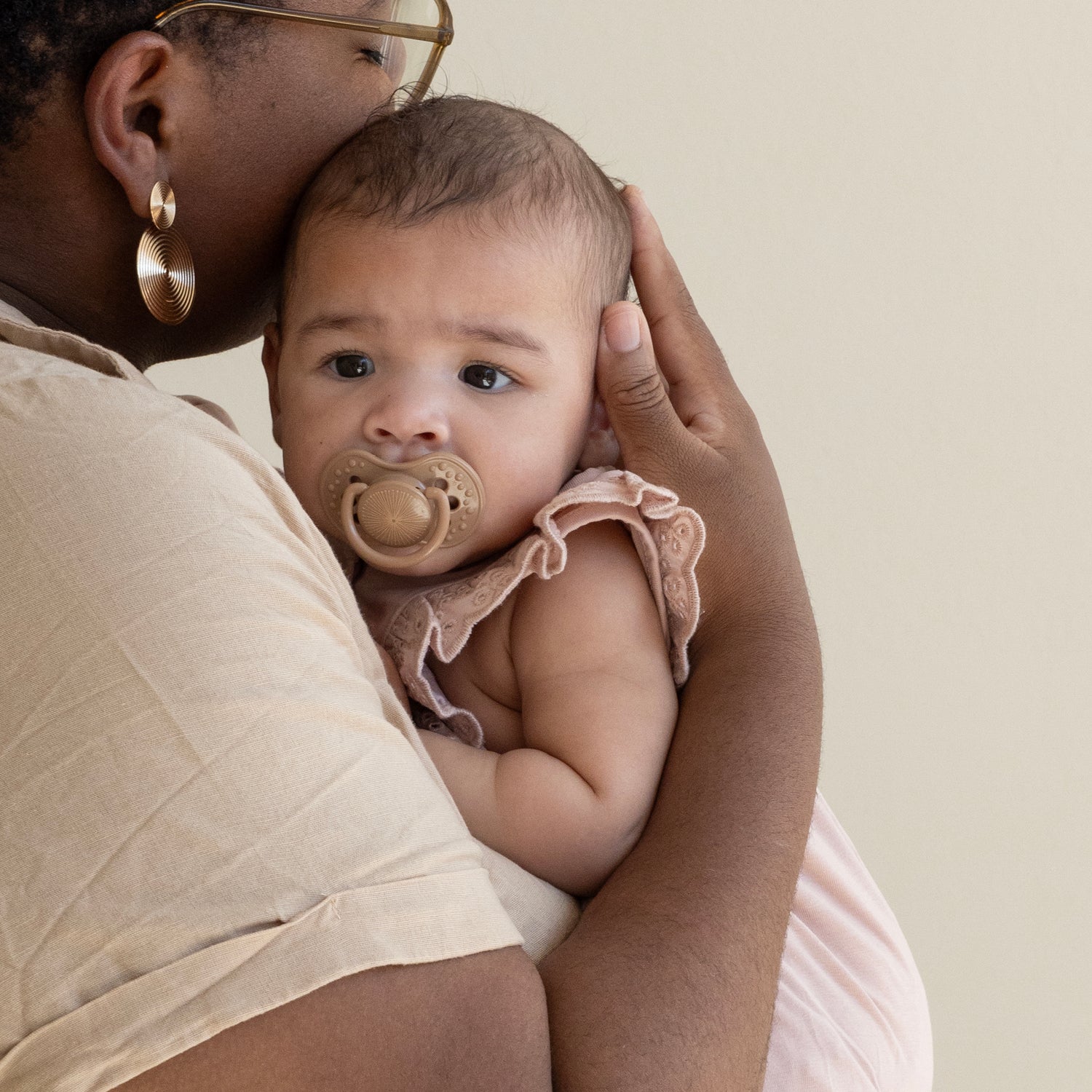 Difrax LOVI Dynamic Pacifier - Harmony - Baby with Dark Brown Pacifier in Mouth in Mothers Arms
